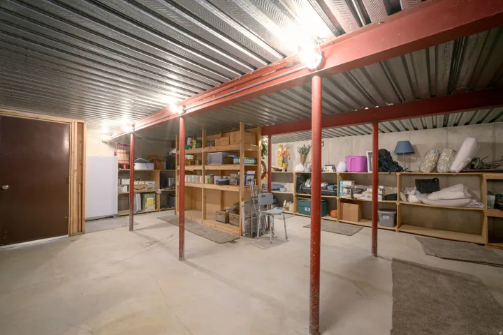 Expansive utility space with concrete flooring, exposed metal ceiling, and built-in shelving