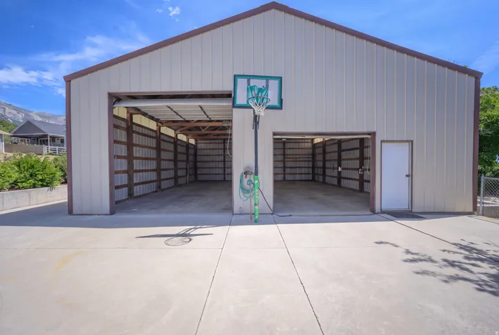 Metal-sided Workshop/Garage/outbuilding with a pitched roof, featuring two large bay doors, a pedestrian door, and a concrete pad