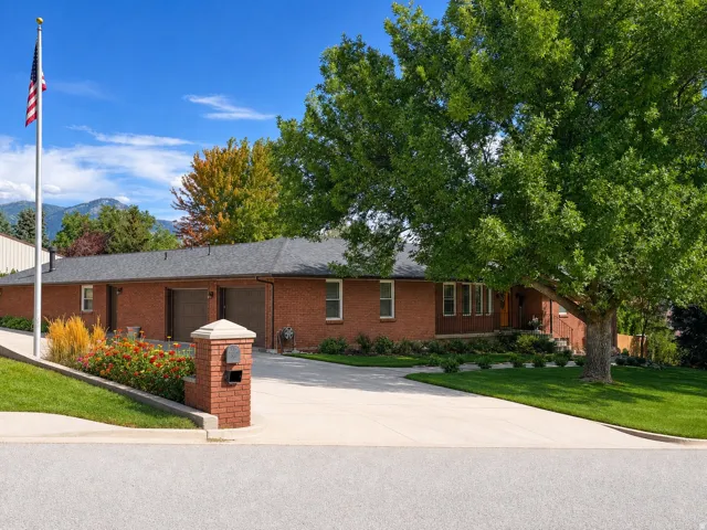 Brick exterior residence with a dark shingle roof, integrated two-car garage, and mature front yard landscaping