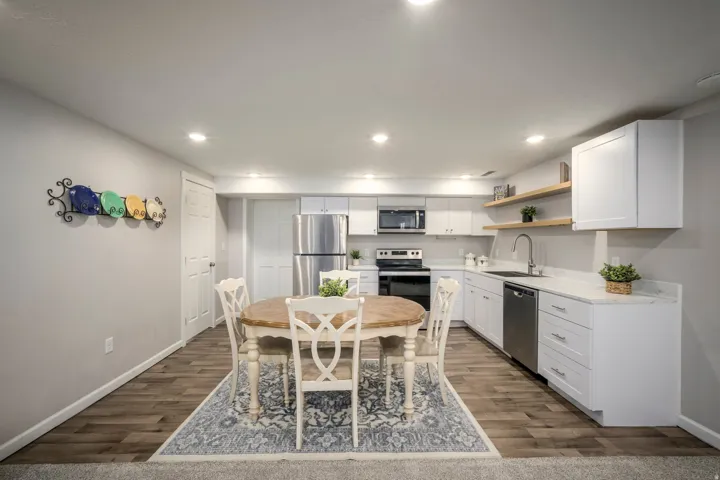 Modern kitchen featuring white cabinetry, light countertops, wood-finish flooring, recessed lighting, and stainless steel appliances