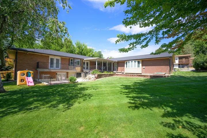 Expansive backyard with a manicured lawn, brick exterior, bay box windows, upper-level balcony, and lower-level patio access a long with deck access off of main level. for main house and apartment