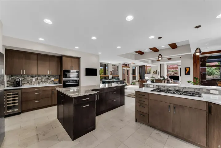 Gourmet kitchen with double islands, integrated cooktop, built-in double ovens, and a beverage cooler