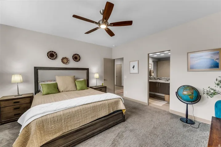 Recessed lighting, ceiling fan with wood-finish blades, soft gray wall paint, upholstered bed frame with nailhead trim, wood-finish nightstands