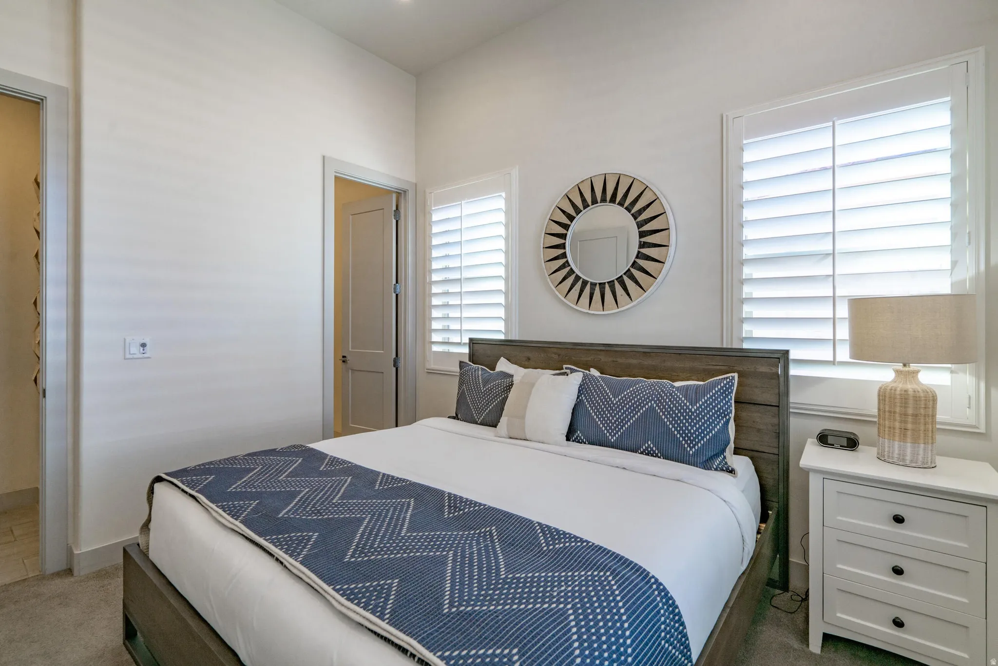 Main Floor Bedroom 2, Wood-finish bed frame, plantation shutters, recessed lighting, and wall-mounted mirror