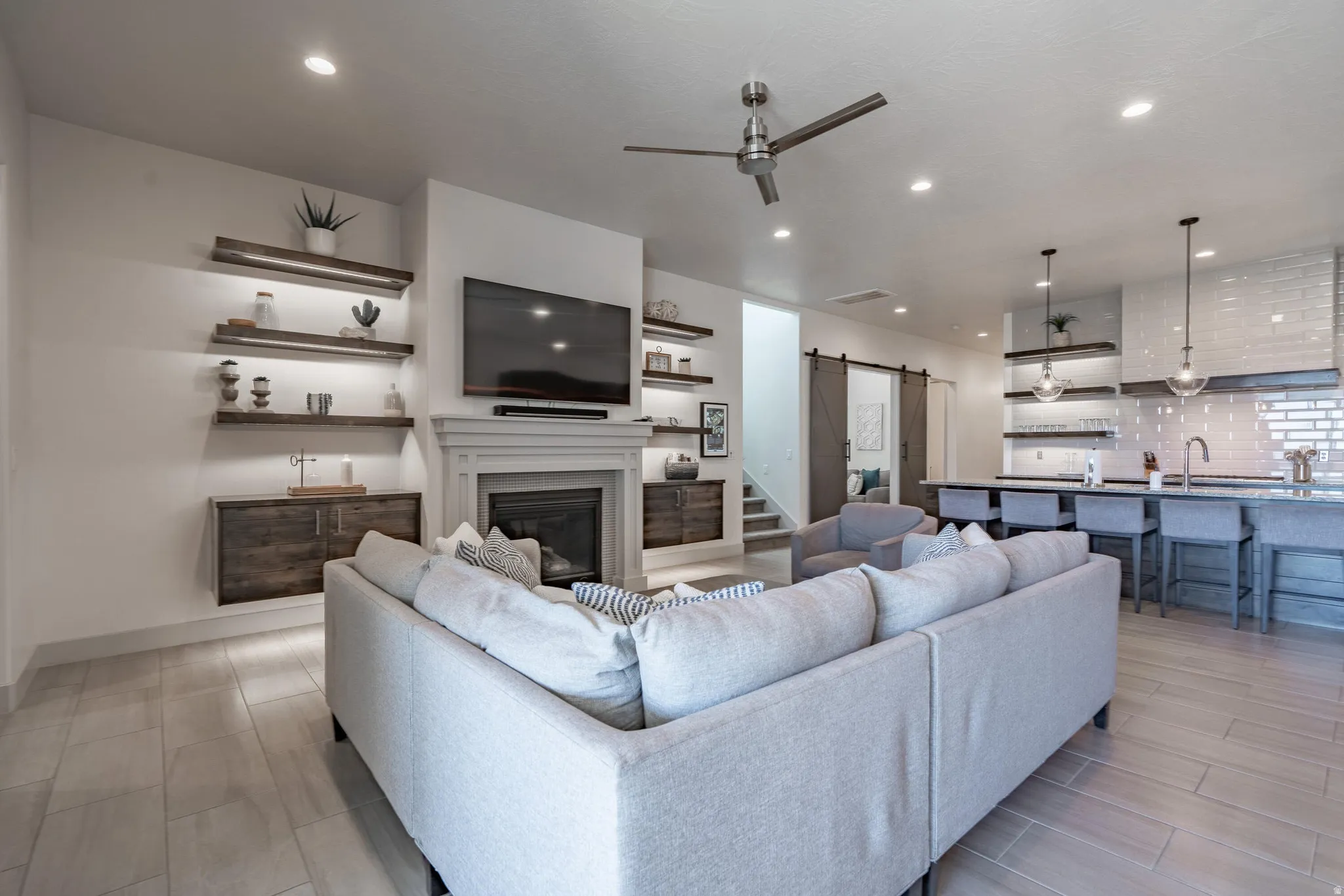 Living space featuring a fireplace with a mantel, built-in shelving, wood-finish flooring, and recessed lighting
