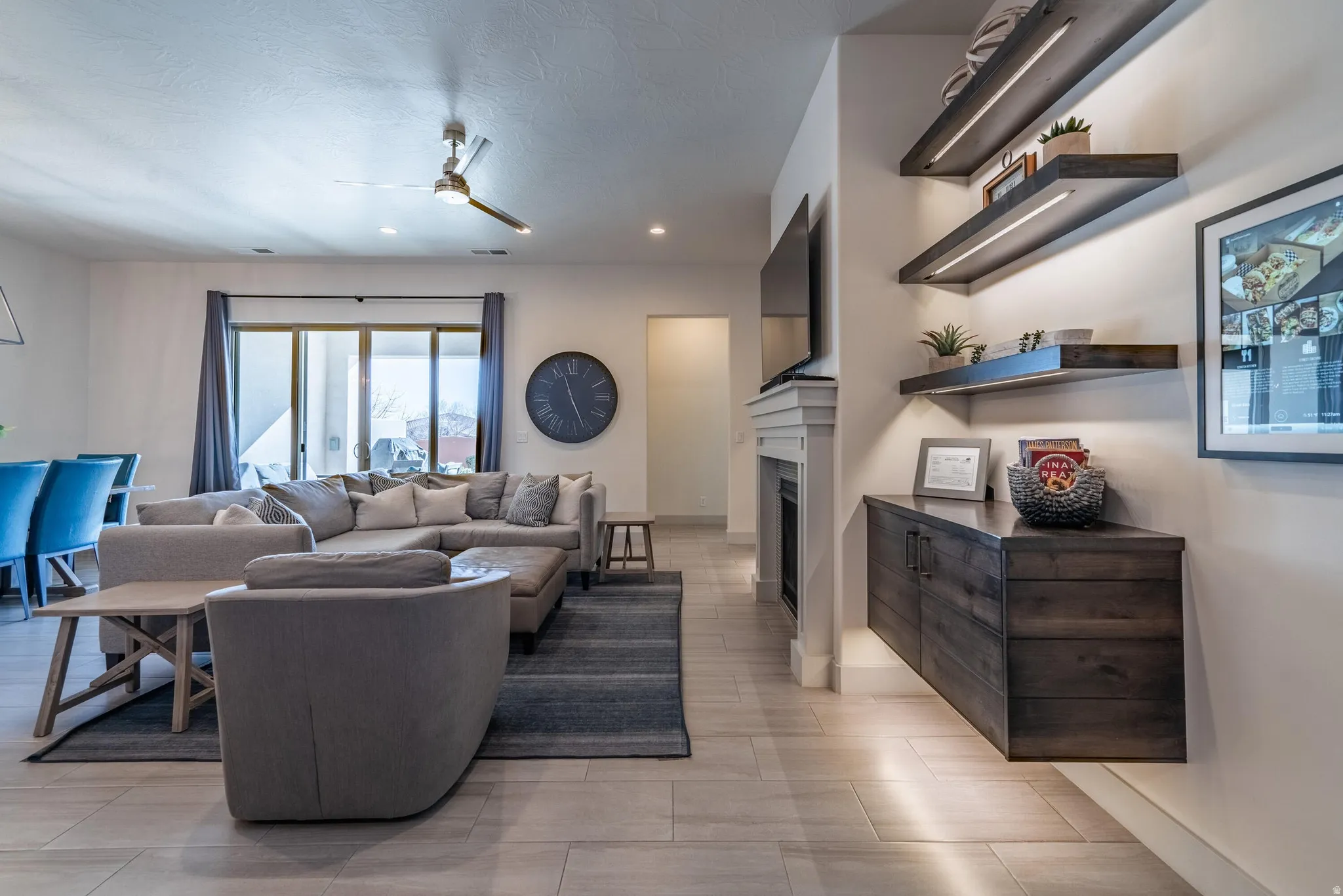 Recessed lighting throughout, wood-finish tile flooring, built-in fireplace with mantel, sliding glass patio door, and built-in wood cabinetry with integrated shelving and lighting