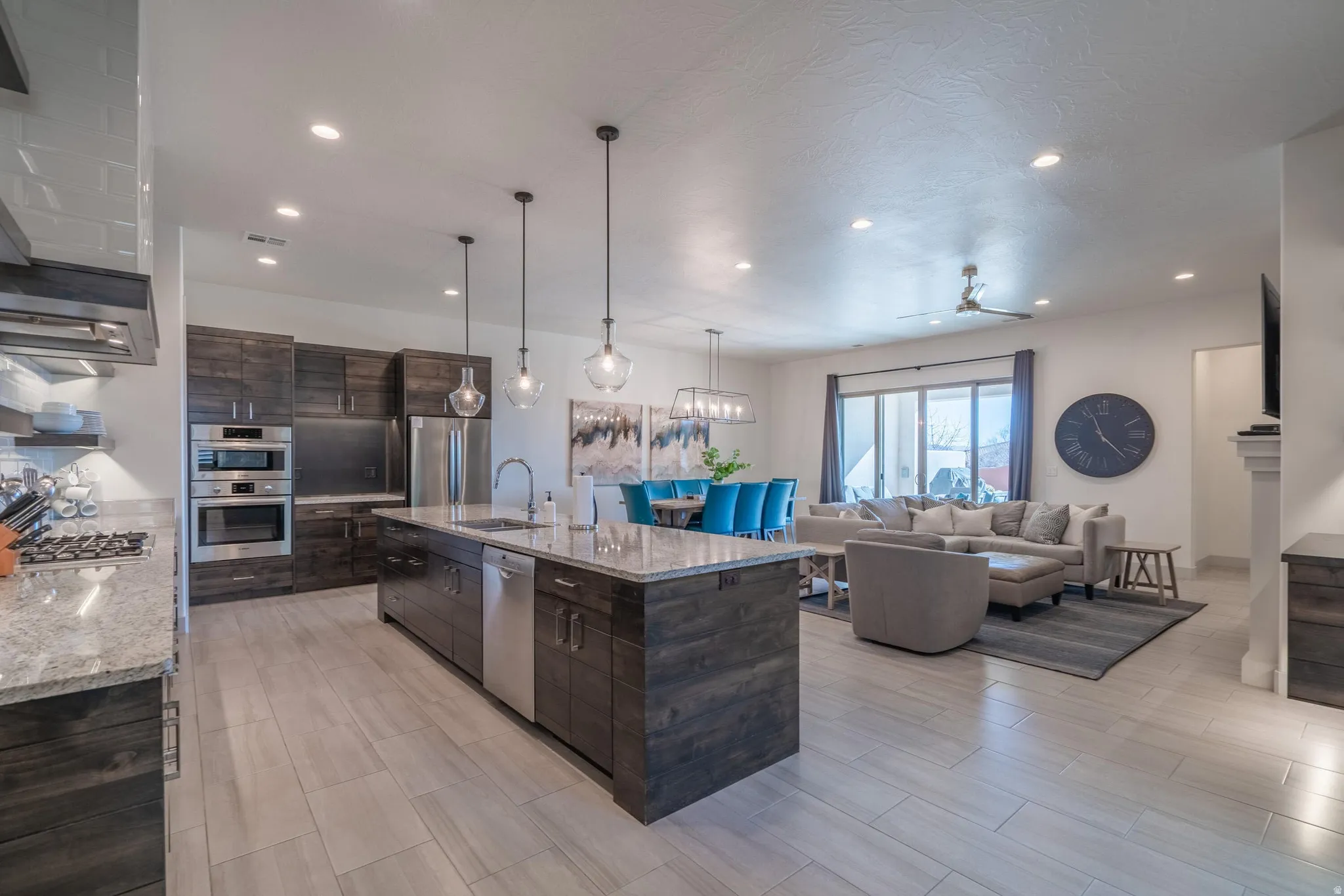 Open-concept living space featuring wood-finish cabinetry, a kitchen island with integrated sink, stainless steel appliances, and a gas range