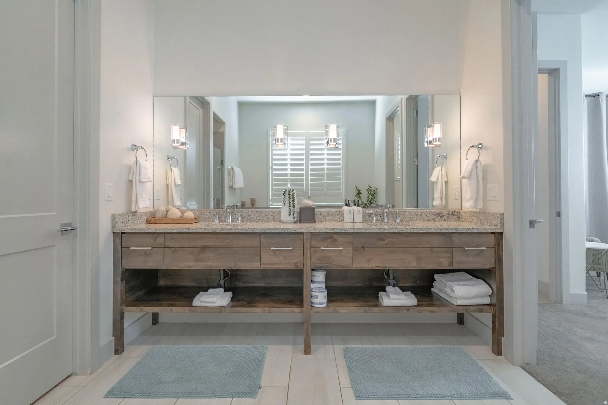 Main Floor Primary Ensuite Dual wood-finish vanity with granite countertop, undermount sinks, and wall-mounted sconces