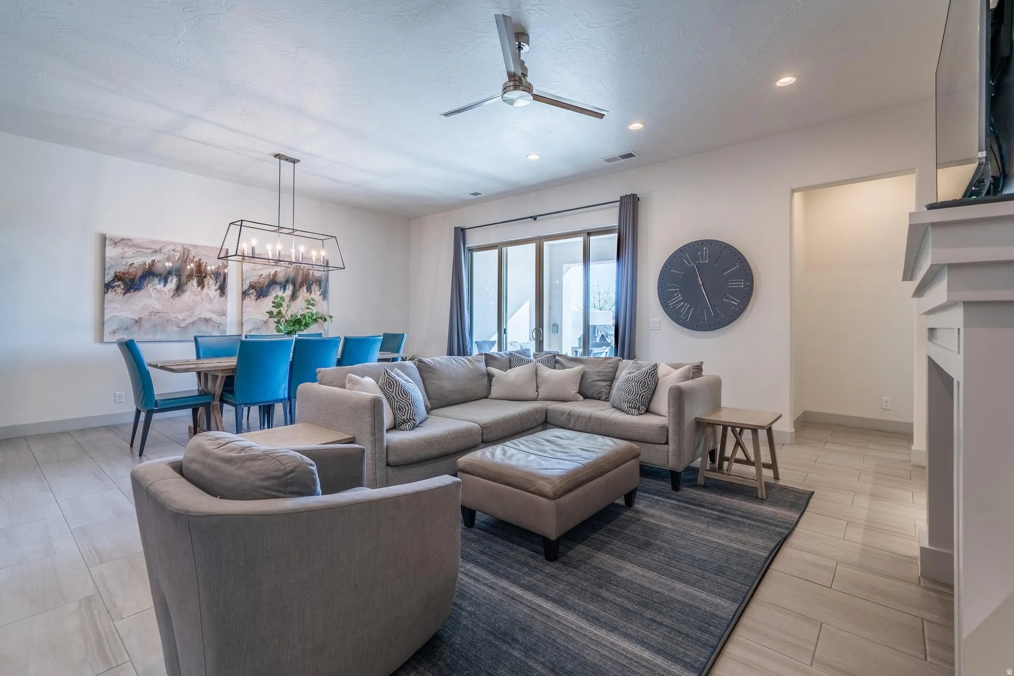 Open-concept living space with light-toned tile flooring, recessed lighting, and a ceiling fan