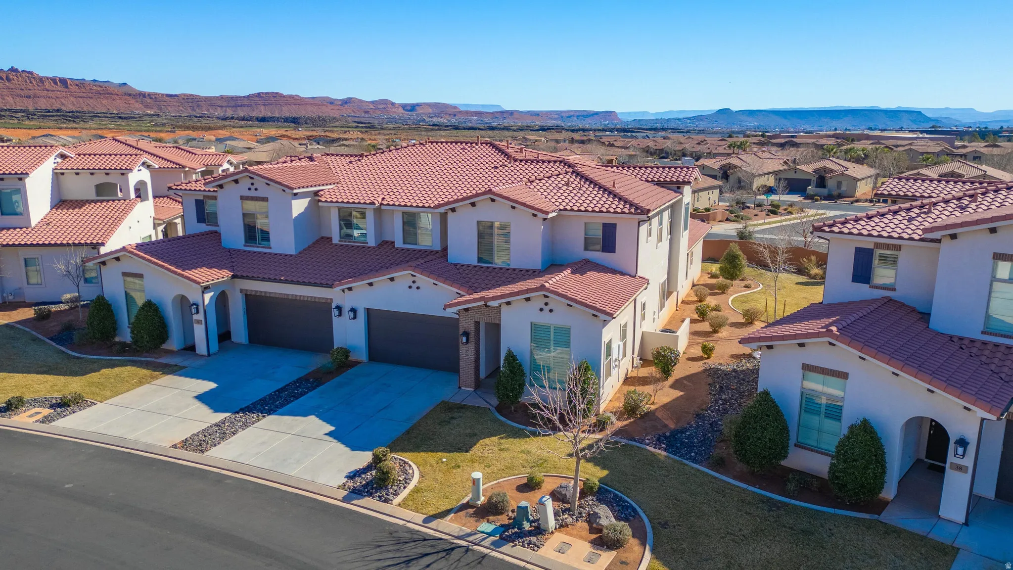 Contemporary stucco exterior with red tile roofing, attached garage and paved driveway