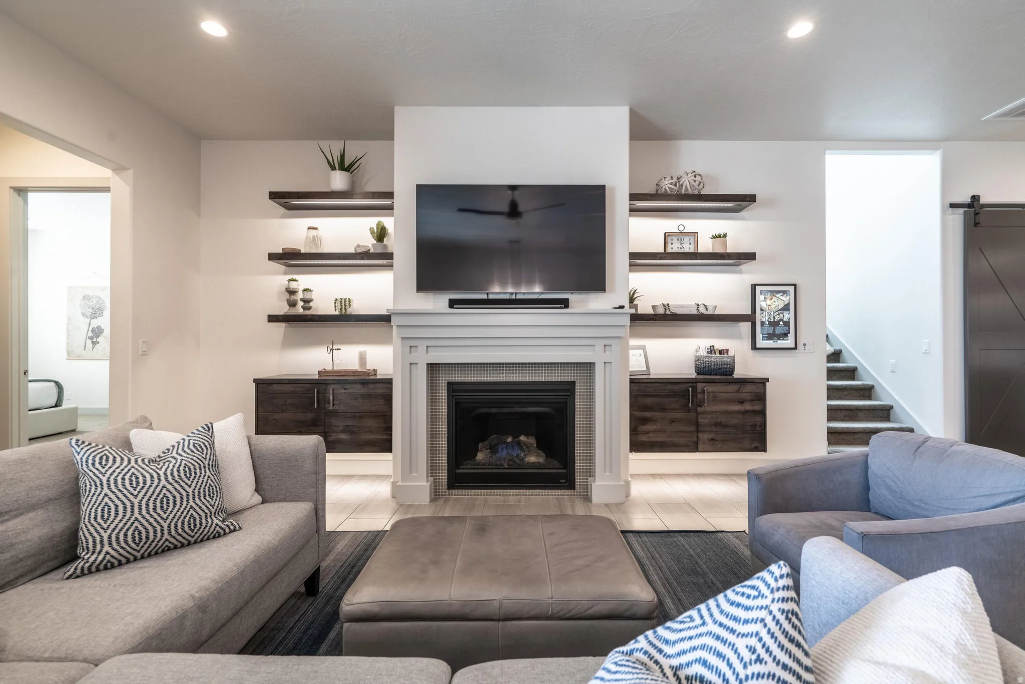 Living area featuring a fireplace with a mantel, built-in shelving with integrated lighting, and wood-finish flooring