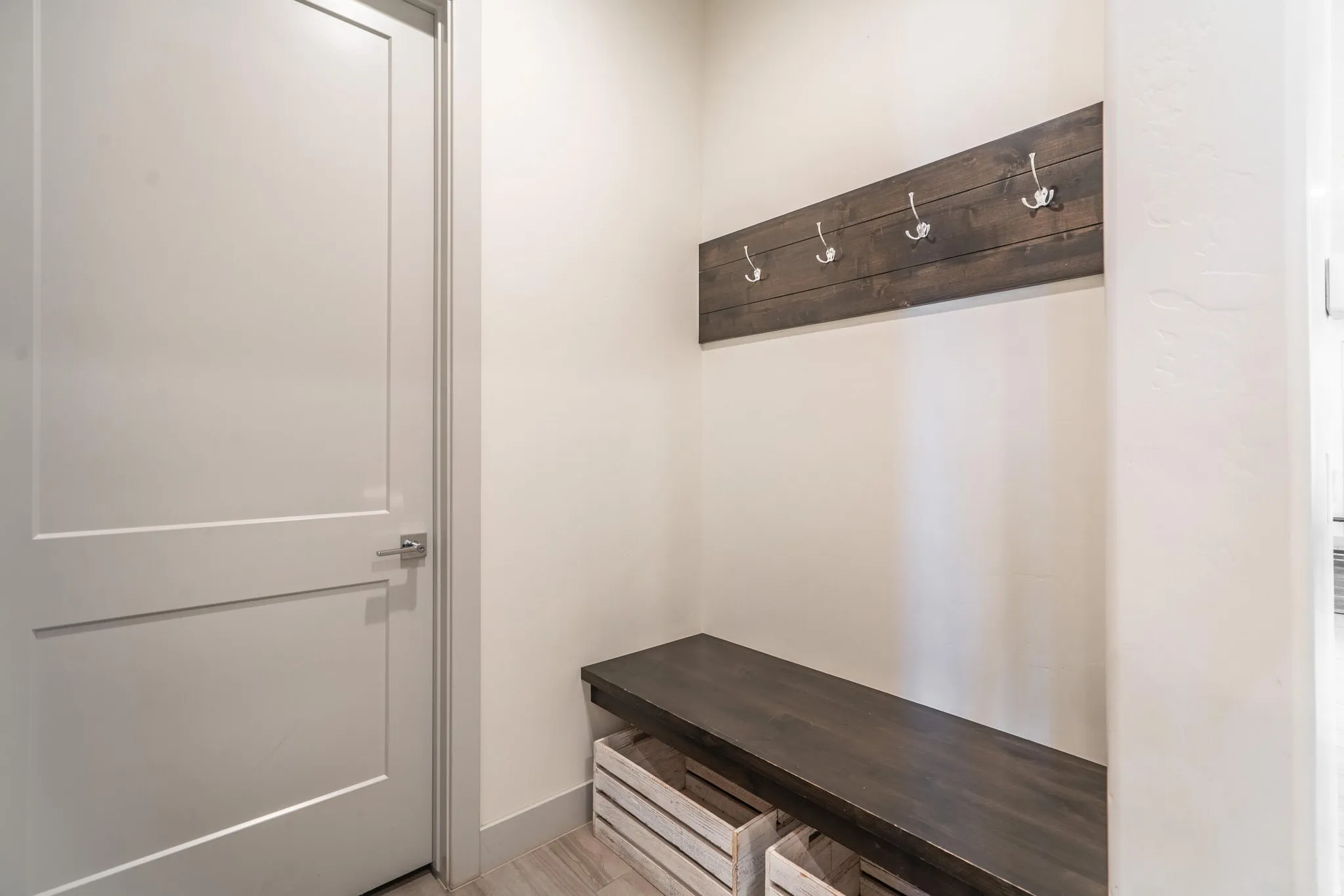 Mudroom area featuring a dark wood-finish bench, coordinating wall-mounted coat rack with five hooks