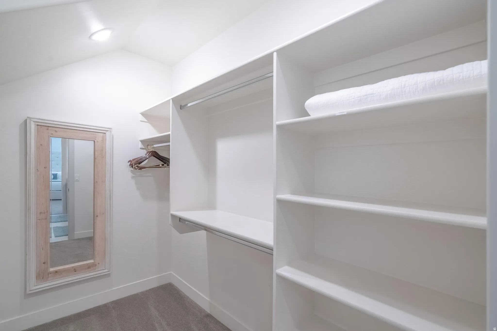 Main Floor Primary Ensuite Closet with recessed lighting, built-in shelving, hanging rods, and a framed mirror