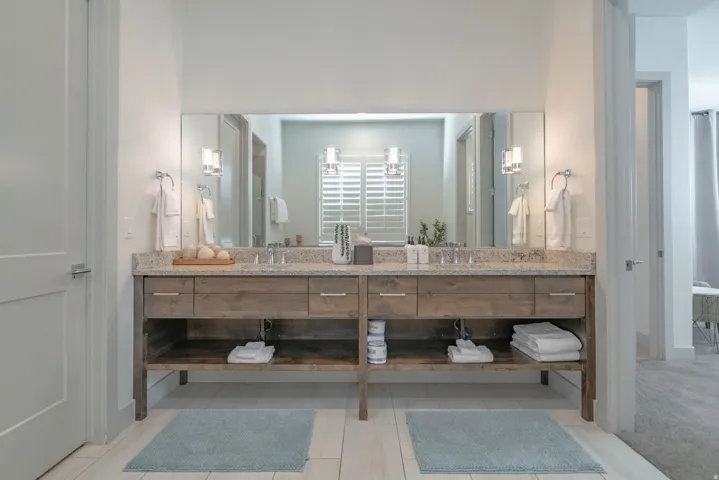 Main Floor Primary Ensuite Dual wood-finish vanity with granite countertop, undermount sinks, and wall-mounted sconces