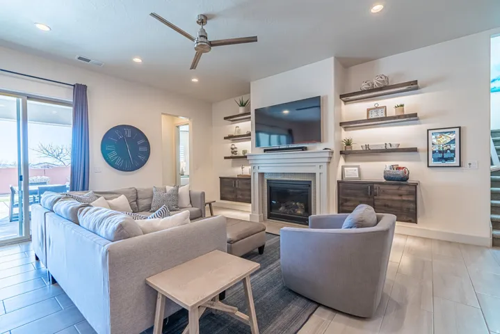 Recessed lighting, ceiling fan, fireplace with mantel, built-in shelving with under-shelf lighting, and wood-finish flooring