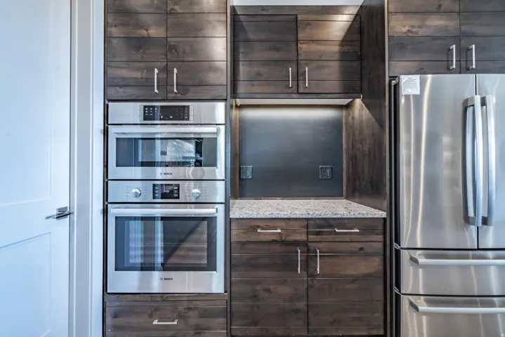 Built-in stainless steel appliances, dark wood-finish cabinetry, under-cabinet lighting, and a granite countertop