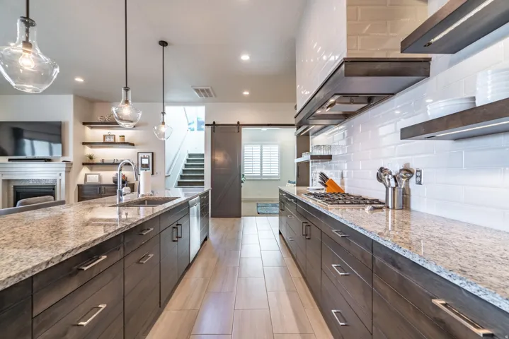 Kitchen featuring granite countertops, wood-finish cabinetry, a gas cooktop, and a subway tile backsplash