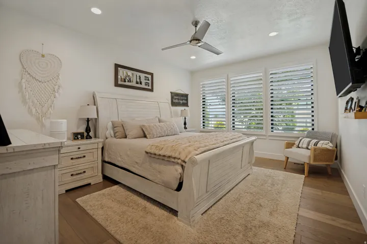 Recessed lighting, ceiling fan, wood-finish flooring, and white plantation shutters on multiple windows