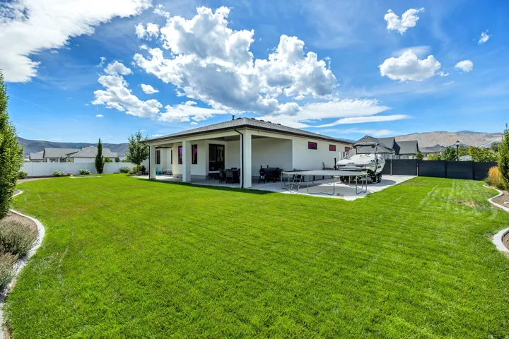 Expansive green lawn with a white privacy fence and curved landscaping beds