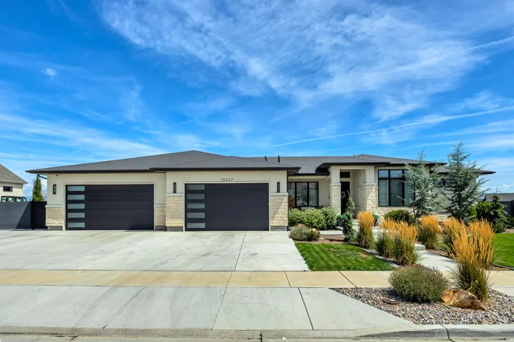 Modern exterior design with stone accents, dark-framed windows, and a multi-car garage with contemporary doors