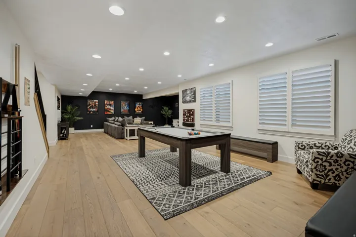 Recessed lighting, wood-finish flooring, and two windows with white louvered shutters