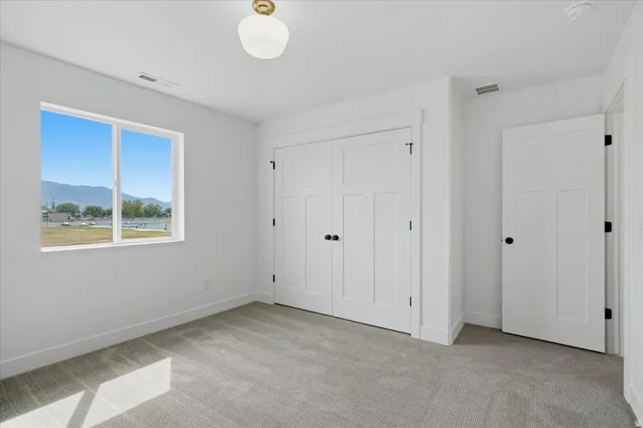 Recessed window with mountain and body of water backdrop, neutral wall tones, low-pile carpet, and white paneled doors with black hardware