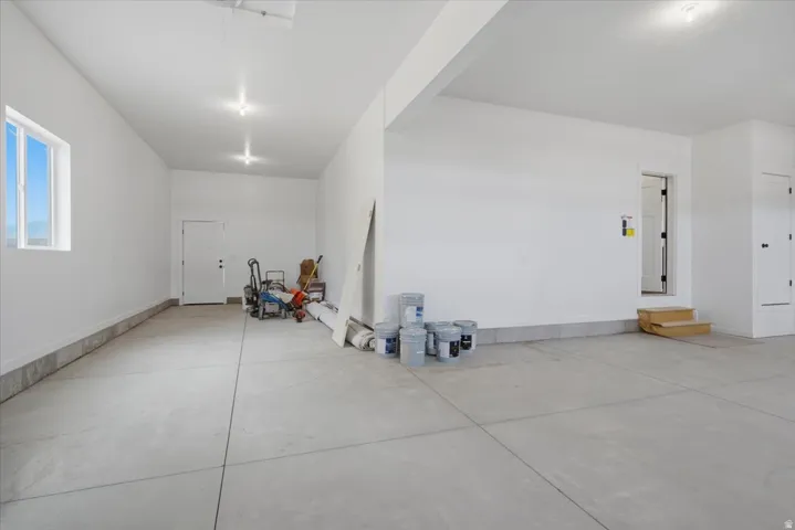 Spacious garage with concrete flooring, recessed lighting, and a white entry door