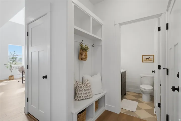 Built-in hall tree with integrated storage, white panel doors with black hardware, and wood-finish flooring extending into the background
