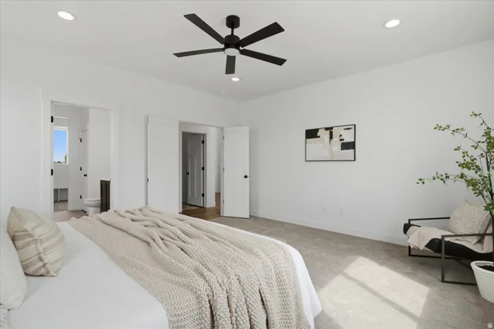Spacious primary bedroom featuring polished concrete flooring, recessed ceiling lighting, and a ceiling fan with dark metal blades