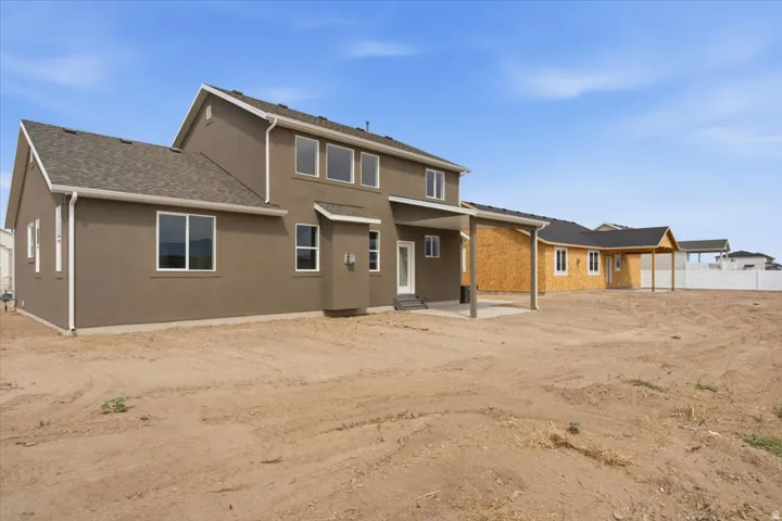 Expansive exterior featuring a stucco finish, multiple windows, a covered patio, and a shingle roof
