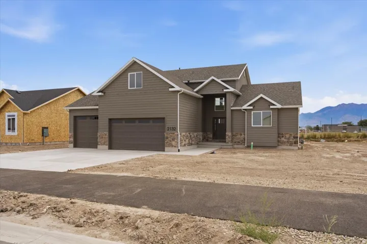 Exterior showcasing a two-car garage, stone veneer accents, and horizontal siding