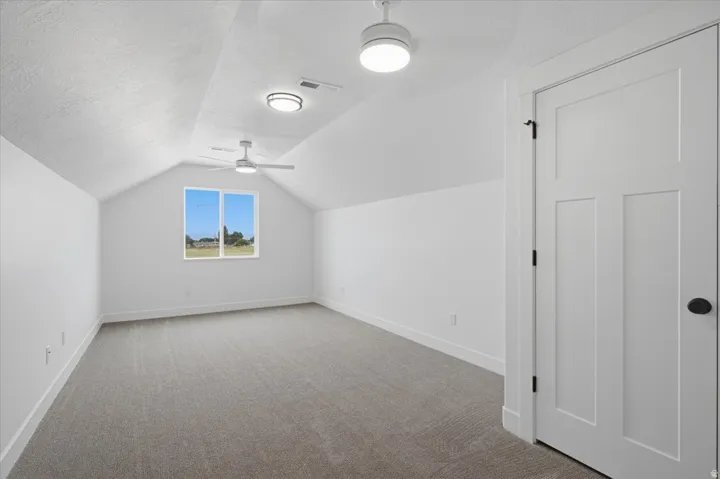 Vaulted ceiling, recessed lighting, ceiling fan, carpet flooring, and a flat-panel door with matte black hardware
