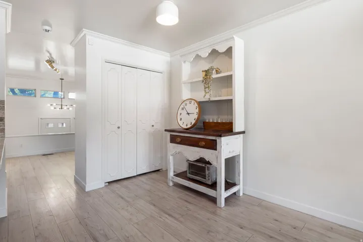 Wood-finish flooring throughout, white walls, and crown molding