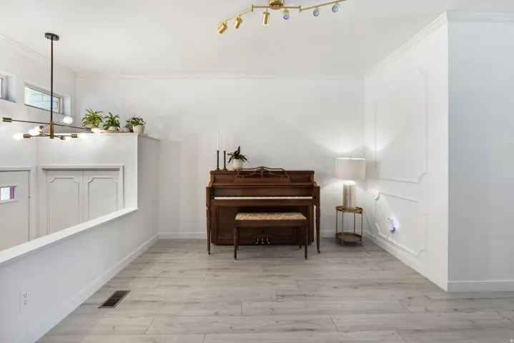 Light wood-finish flooring, white walls, and a decorative wall panel accent