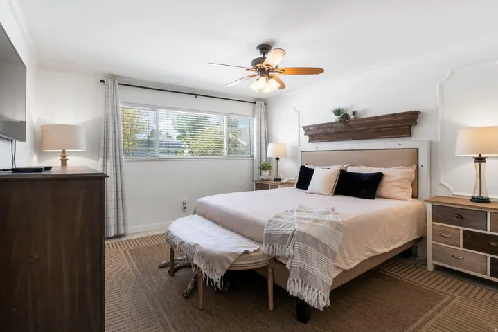 Expansive window with blinds, ceiling fan, crown molding, and wood-finish flooring