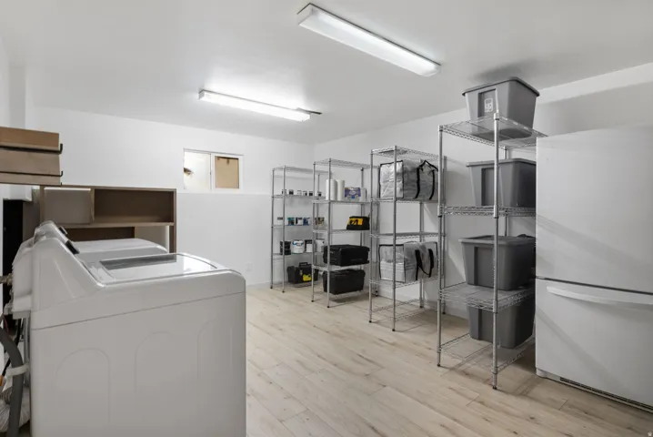 Laundry area with wood-finish flooring, built-in shelving, and overhead fluorescent lighting