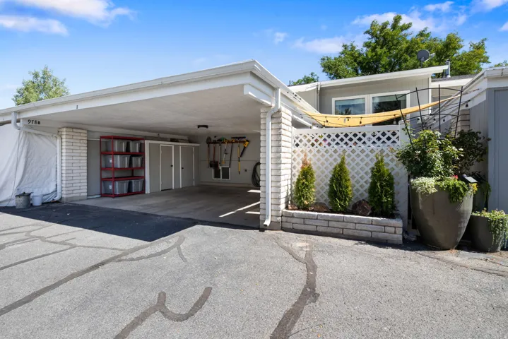 Covered carport with storage units, brick columns, and a lattice privacy screen