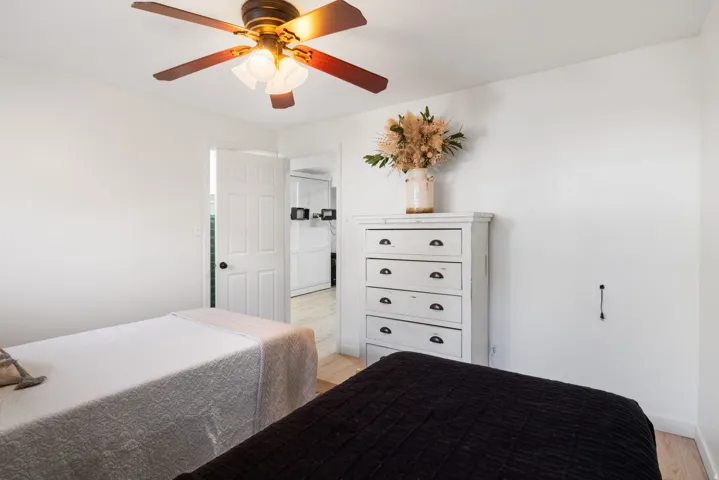 Ceiling fan with light fixture, white interior door, light wood-finish flooring
