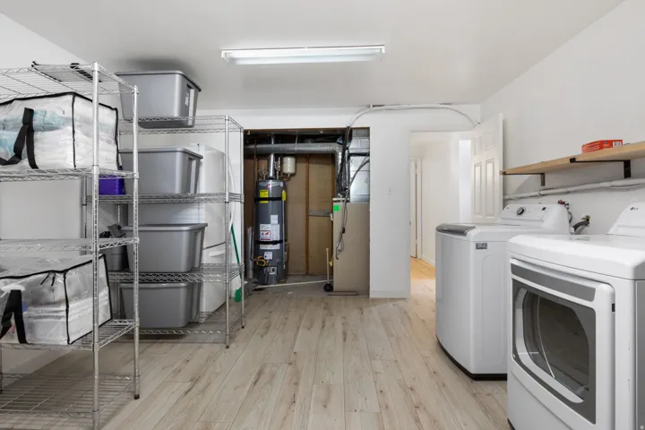 Laundry area featuring wood-finish flooring and wall-mounted shelving