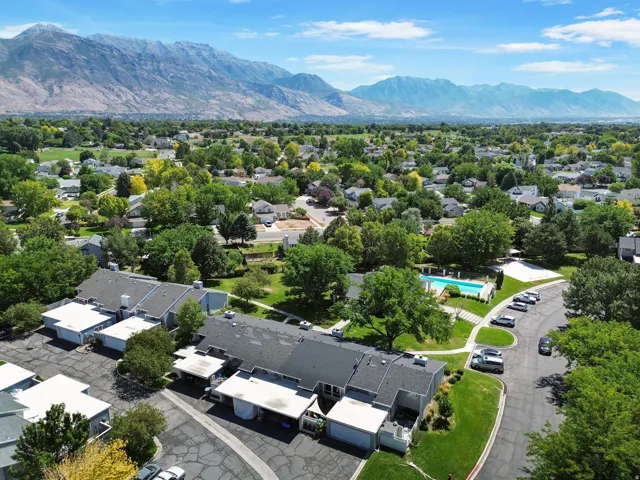 Community pool with surrounding concrete deck, mature trees, and mountain scenery