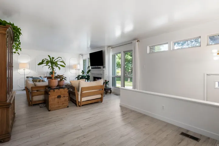 Wood-finish flooring throughout, white walls, decorative wall paneling, and an integrated fireplace