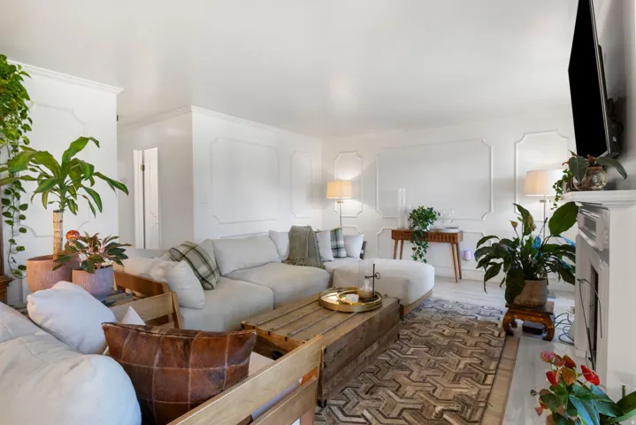 Decorative wall molding, crown molding, light wood-finish flooring, white fireplace, and recessed lighting