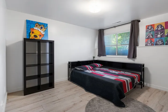 Light wood-finish flooring, white walls, and a window with blinds and dark curtains