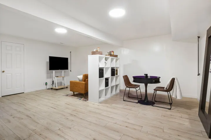 Open-concept room featuring wood-finish flooring, recessed lighting, and a white interior door