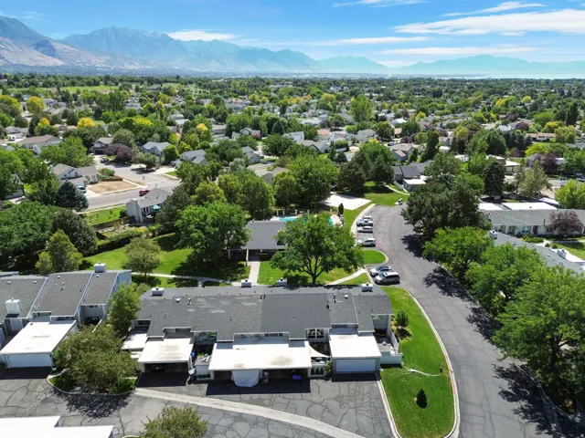 Mountain backdrop, expansive green spaces, mature trees, paved roadways, residential buildings