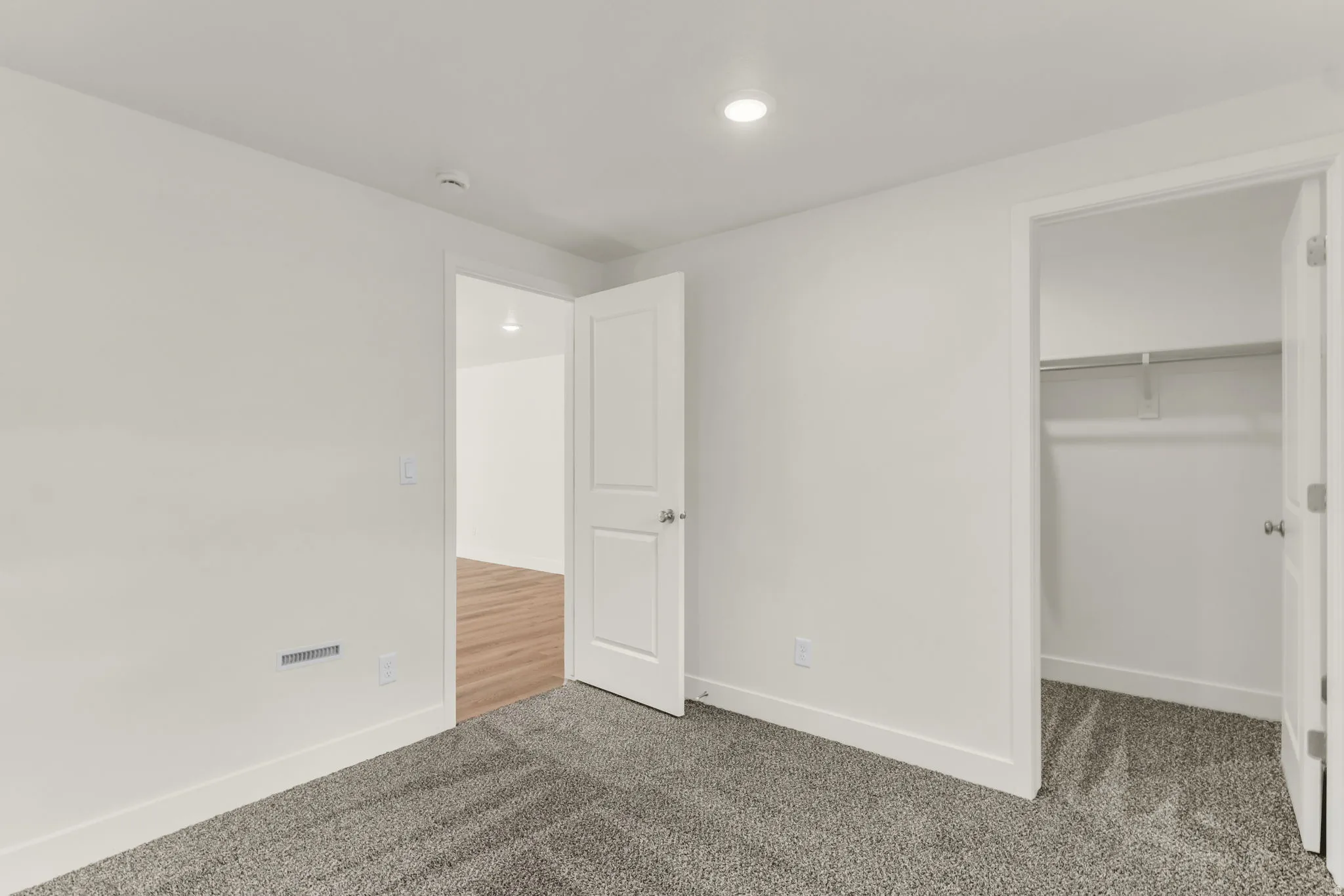Wall-to-wall carpeting, overhead recessed lighting, and a built-in closet with shelving