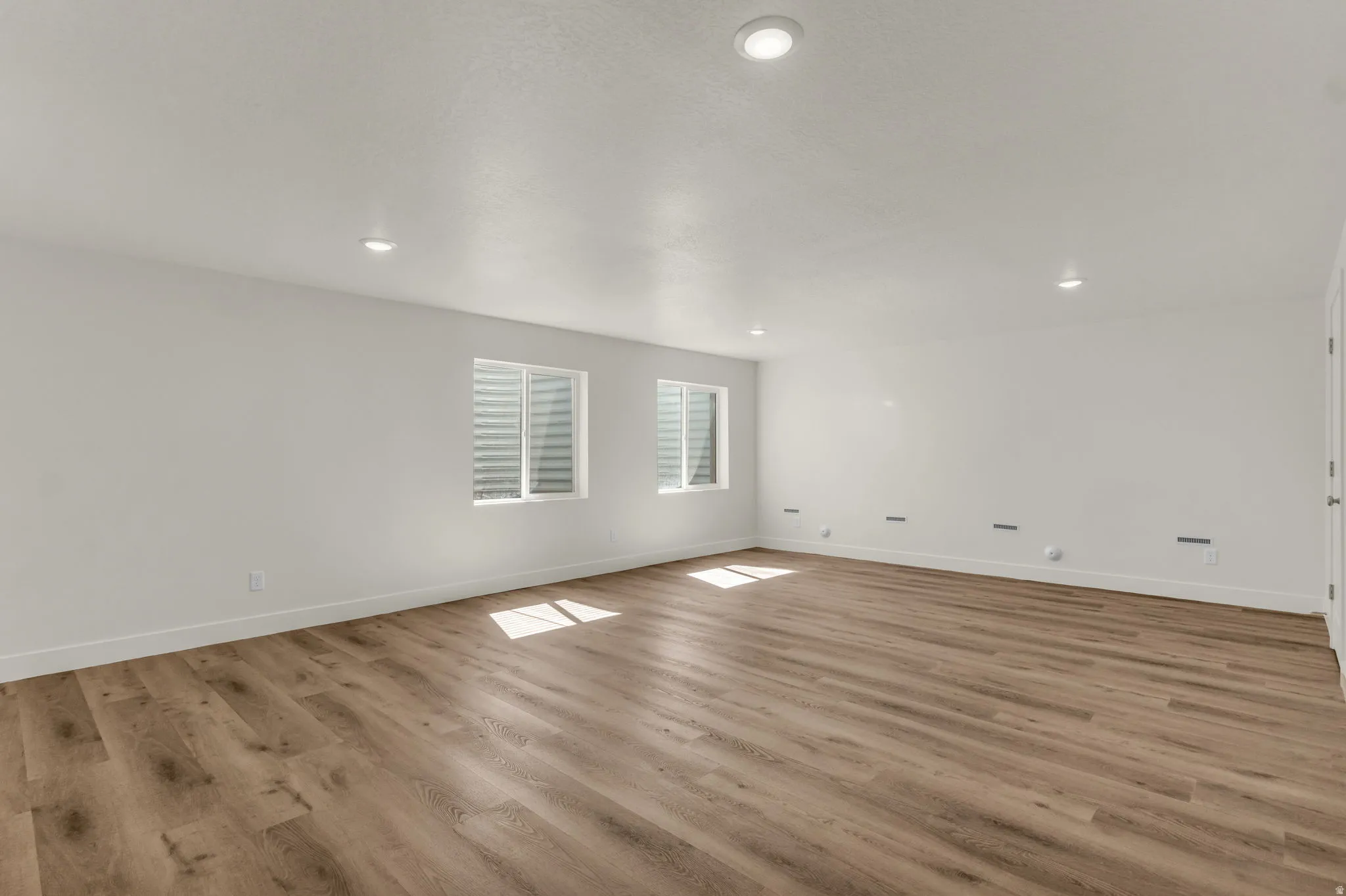 Expansive room featuring wood-finish flooring, recessed lighting, and white walls