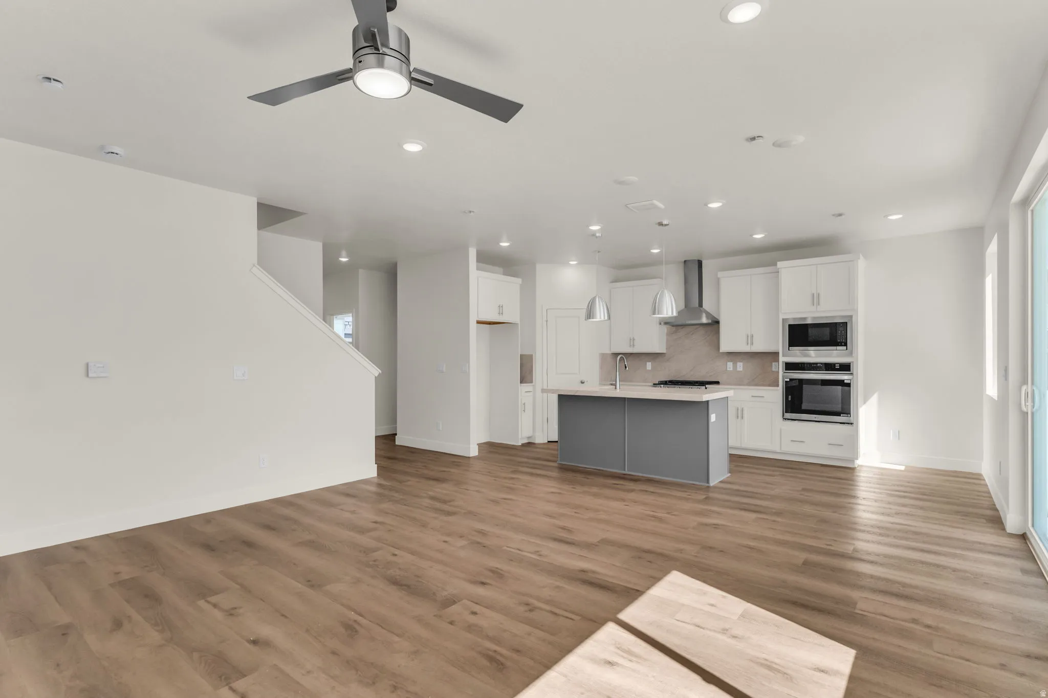 Open-concept living area with wood-finish flooring, recessed lighting, and a contemporary ceiling fan