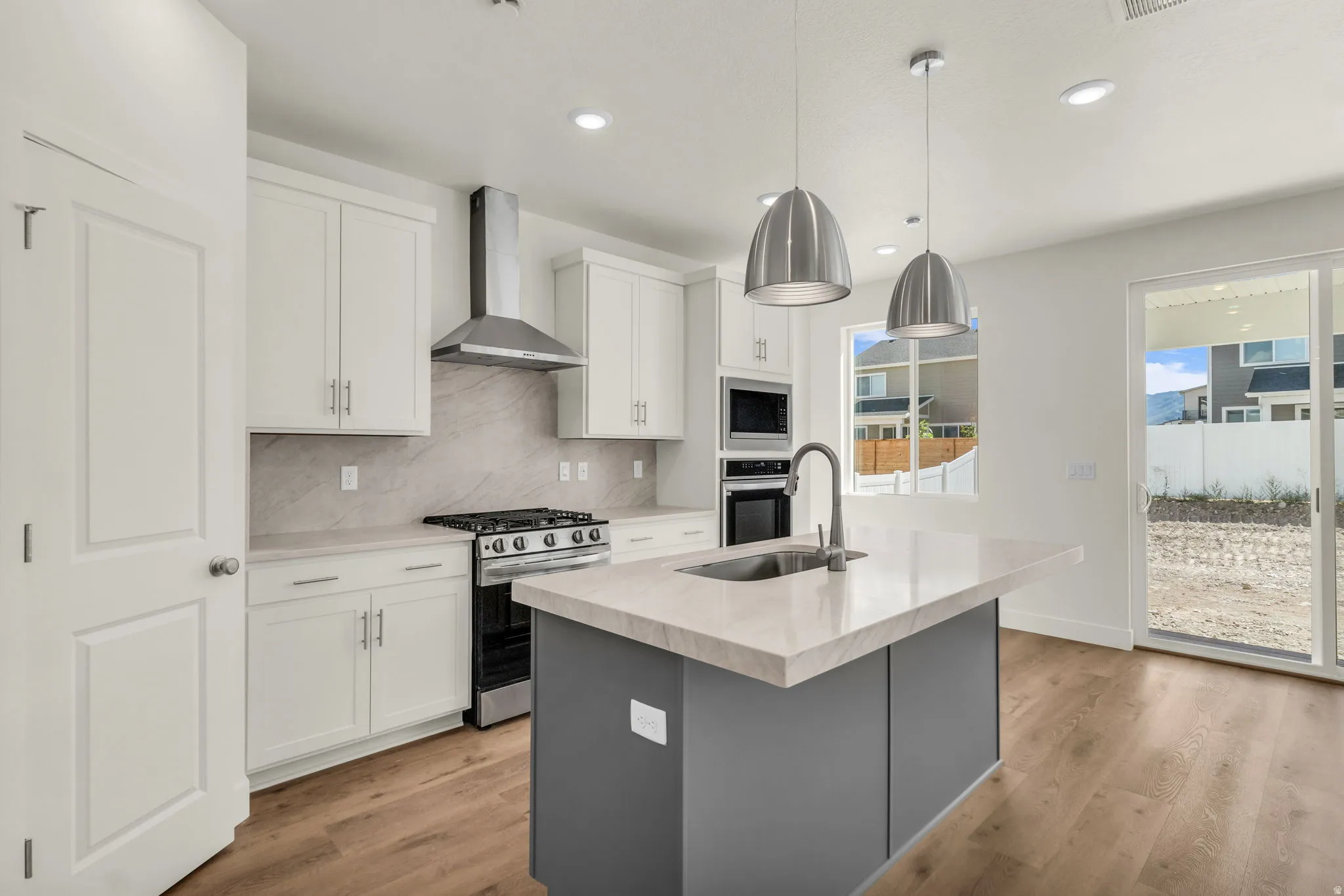 Modern kitchen featuring an island with a built-in sink, stainless steel appliances, and white cabinetry