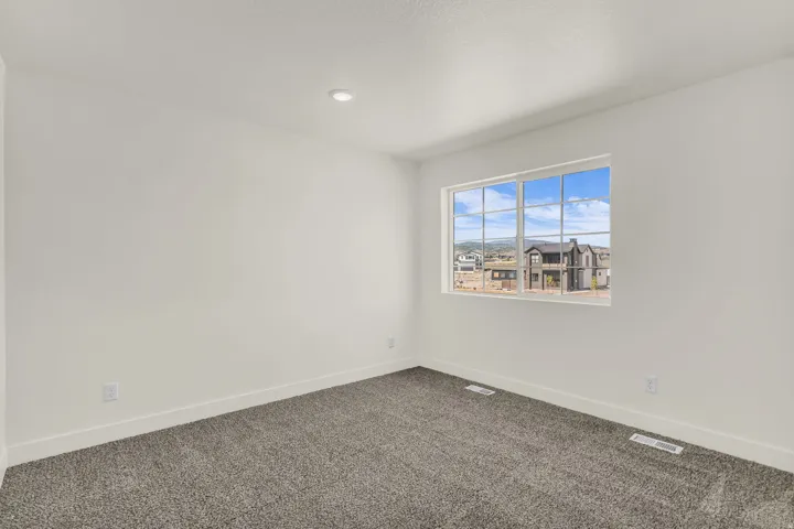 Recessed ceiling lighting, white painted walls, gray carpeting, and a multi-pane window
